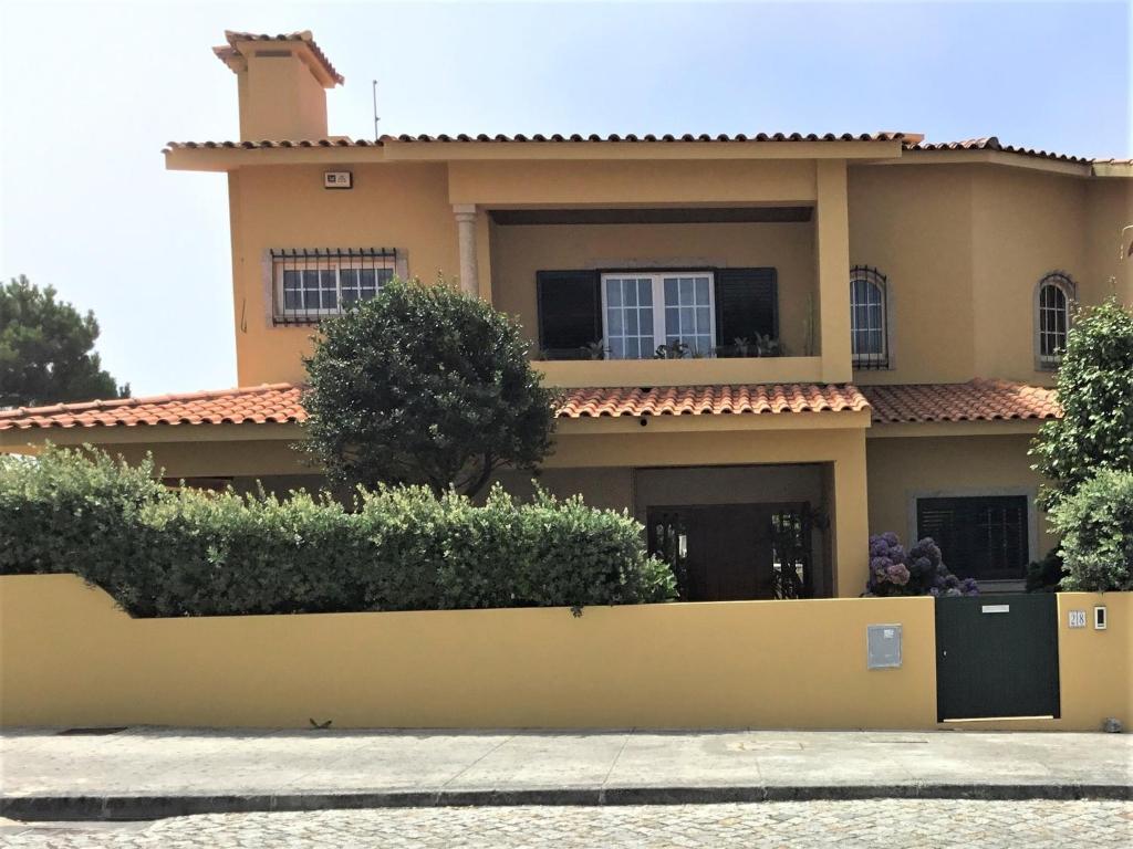 ein Haus mit einem gelben Zaun davor in der Unterkunft Ferienhaus Casa do mar mit seitlichem Meerblick in Vila Chã