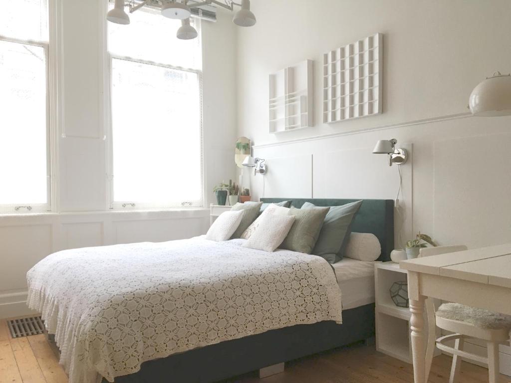 a bedroom with a bed and a desk and windows at guestroom traza 37 in Amsterdam