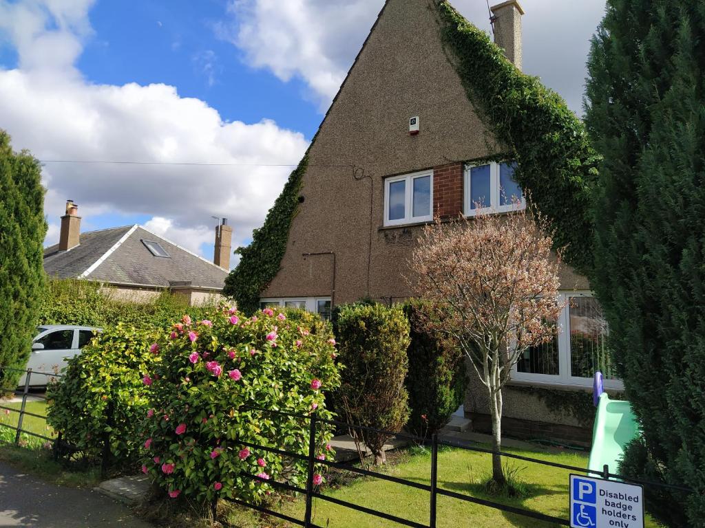 a house with bushes and flowers in front of it at Self Catering Studio in Juniper Green