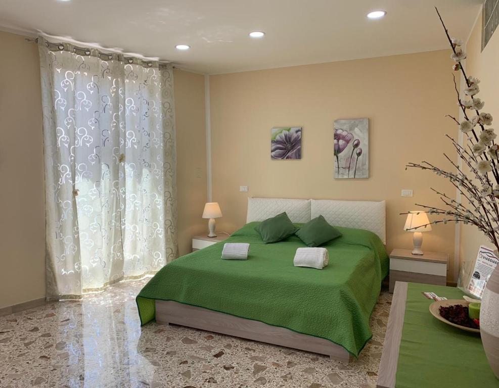 a bedroom with a green bed with two pillows at Si Viaggiare Apartments in Partinico