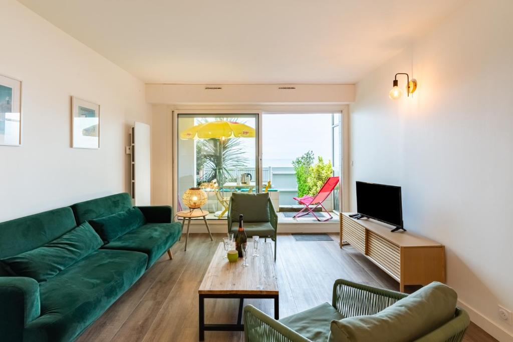 uma sala de estar com um sofá verde e uma mesa em Le Grand Léjon em Pléneuf-Val-André