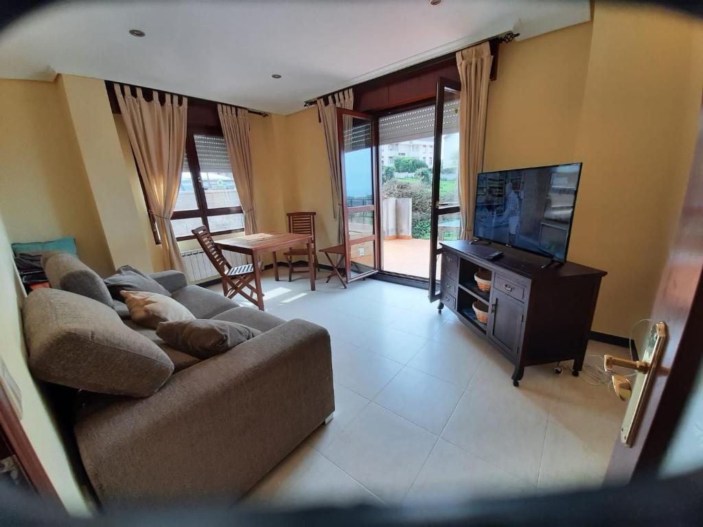 a living room with a couch and a flat screen tv at Con vistas al mar y aparcamiento gratis in Suances