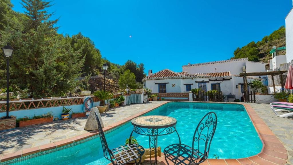 een zwembad met een tafel en stoelen naast een huis bij Casa Tejeda Frigiliana by Ruralidays in Frigiliana