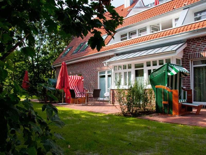 una casa con un patio trasero con una estructura de juegos en Suitenhotel Idyll Heckenrose, en Langeoog