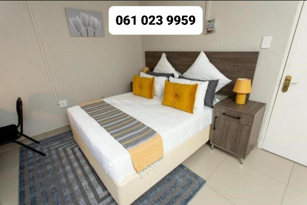 um quarto com uma cama grande e almofadas amarelas em The Hide On Claremont em Pretoria