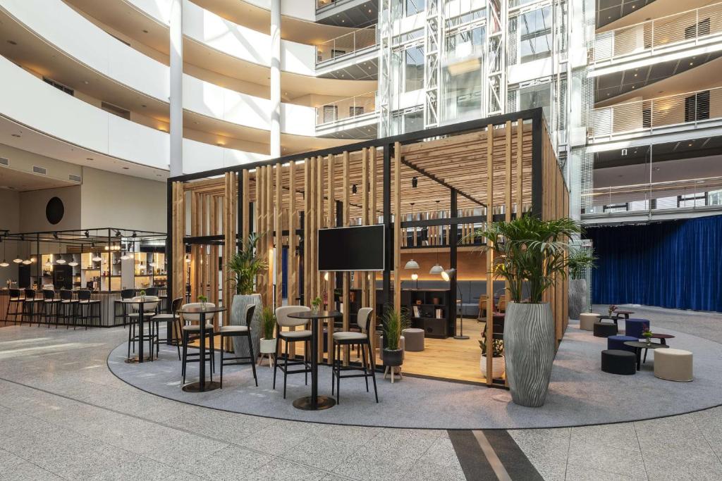 eine Lobby mit Tischen und Stühlen in einem Gebäude in der Unterkunft NH Düsseldorf City in Düsseldorf