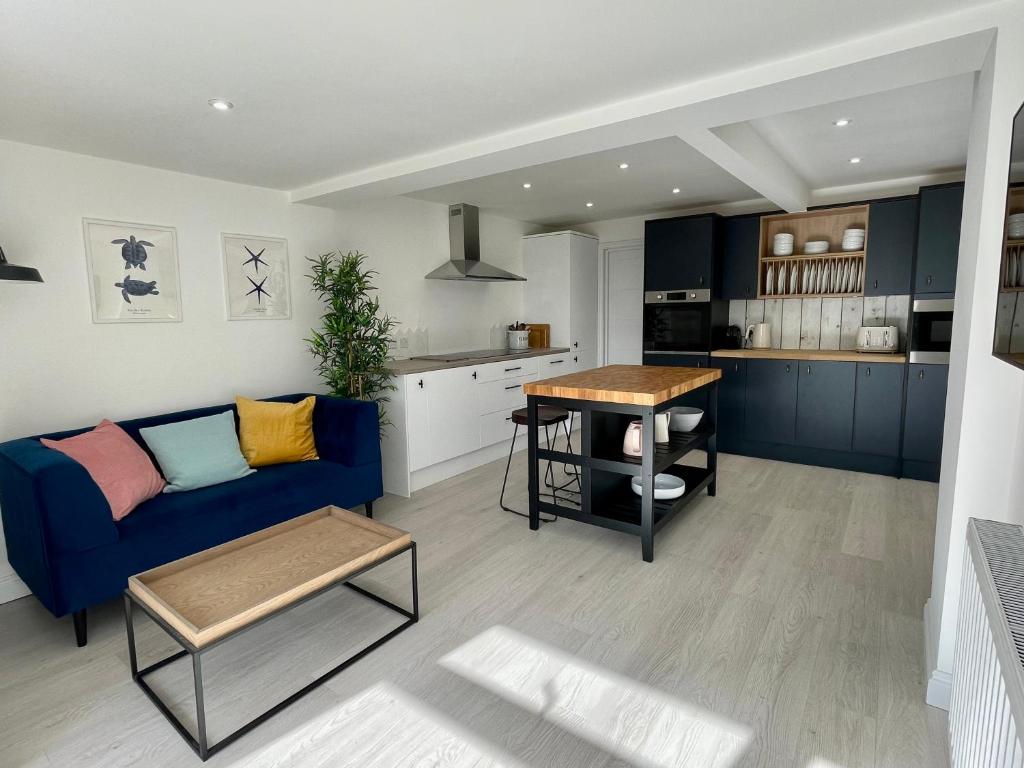 a living room with a blue couch and a kitchen at Island House in West Mersea