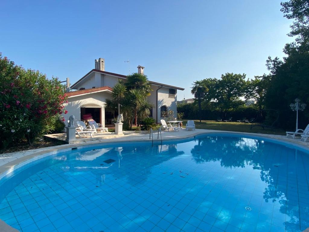 a large blue swimming pool in front of a house at Villa Lorivita in Bevazzana