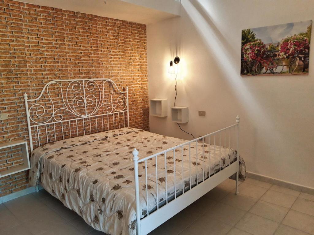Cama blanca en habitación con pared de ladrillo en Agriturismo Il Cipresso, en Vada