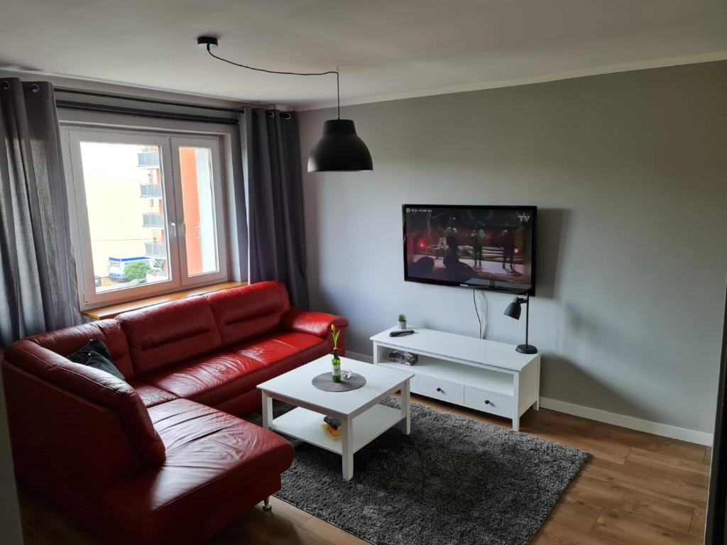 sala de estar con sofá rojo y TV en Apartament Parkowa Szczecin Polska, en Szczecin