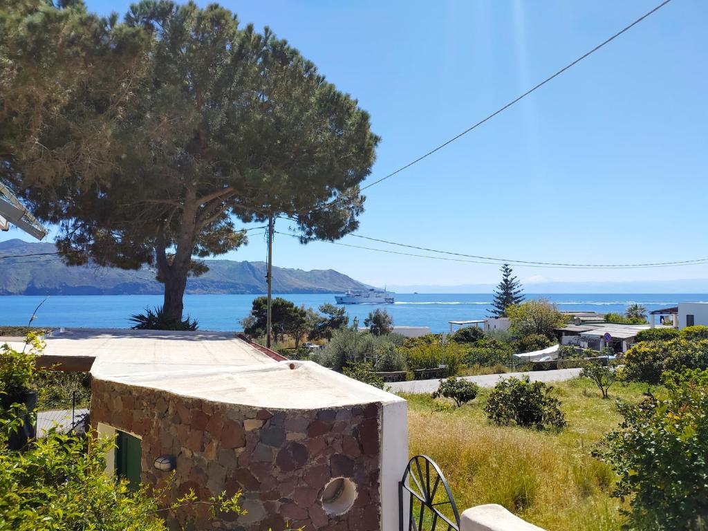 una casa con un árbol y el océano en el fondo en Il Villaggio Eoliano, en Santa Marina Salina