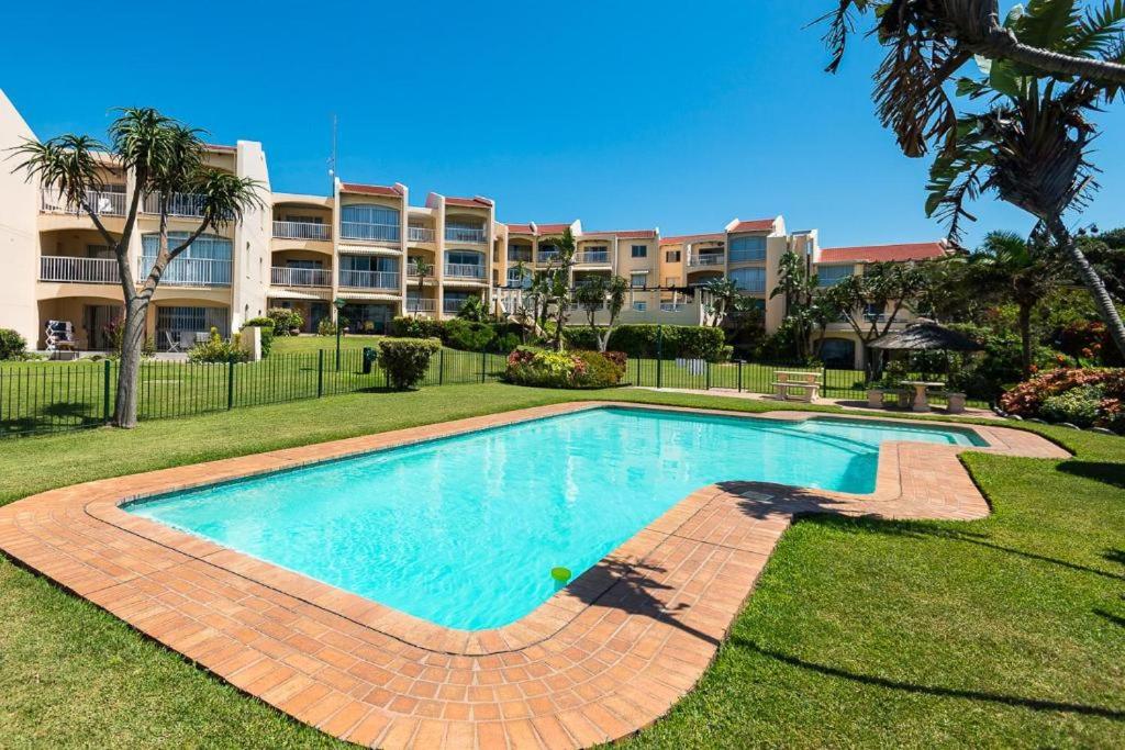 a swimming pool in front of a large apartment building at Seaside At 22 Sandpiper in Ballito