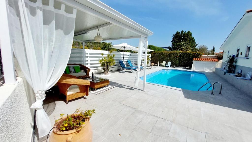 eine Terrasse mit einem Pool und einem weißen Sonnenschirm in der Unterkunft Villa Salieri: Coral Bay villa with private pool in Peyia
