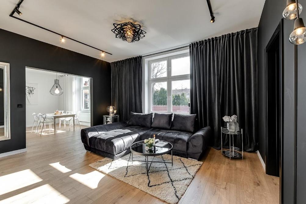 a living room with a leather couch and a table at Jan III Sobieski - Luksusowy apartament L z darmowym prywatnym parkingiem in Gliwice