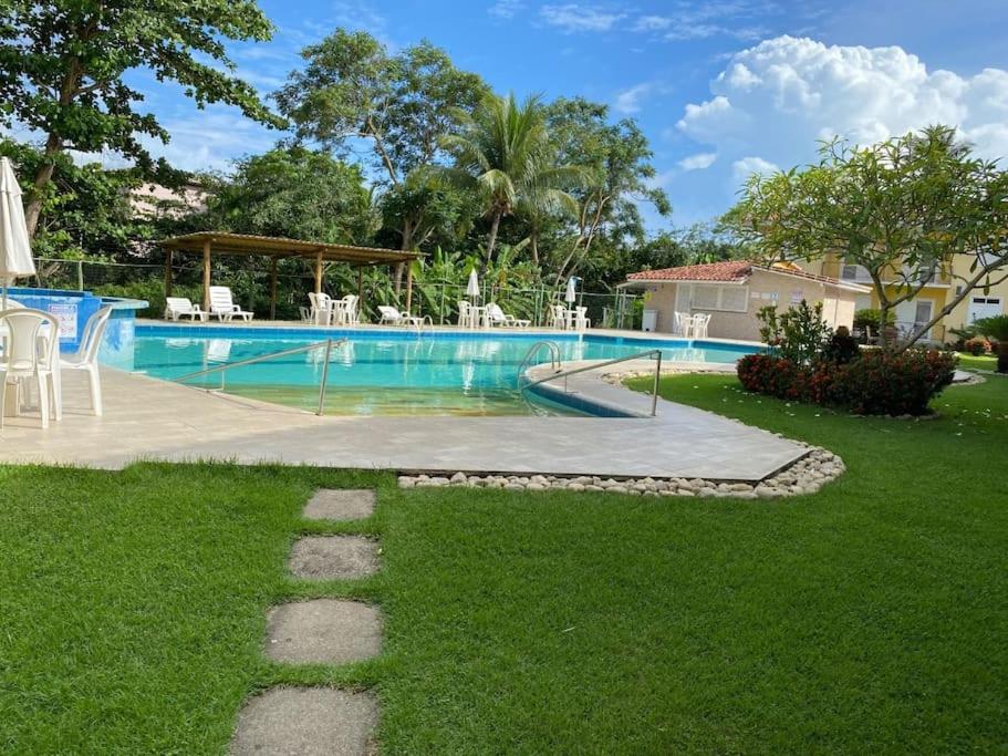 a swimming pool in a yard with green grass at Boulevard da Praia Apart Hotel - Porto Seguro - Frente da Praia de Taperapuan in Porto Seguro