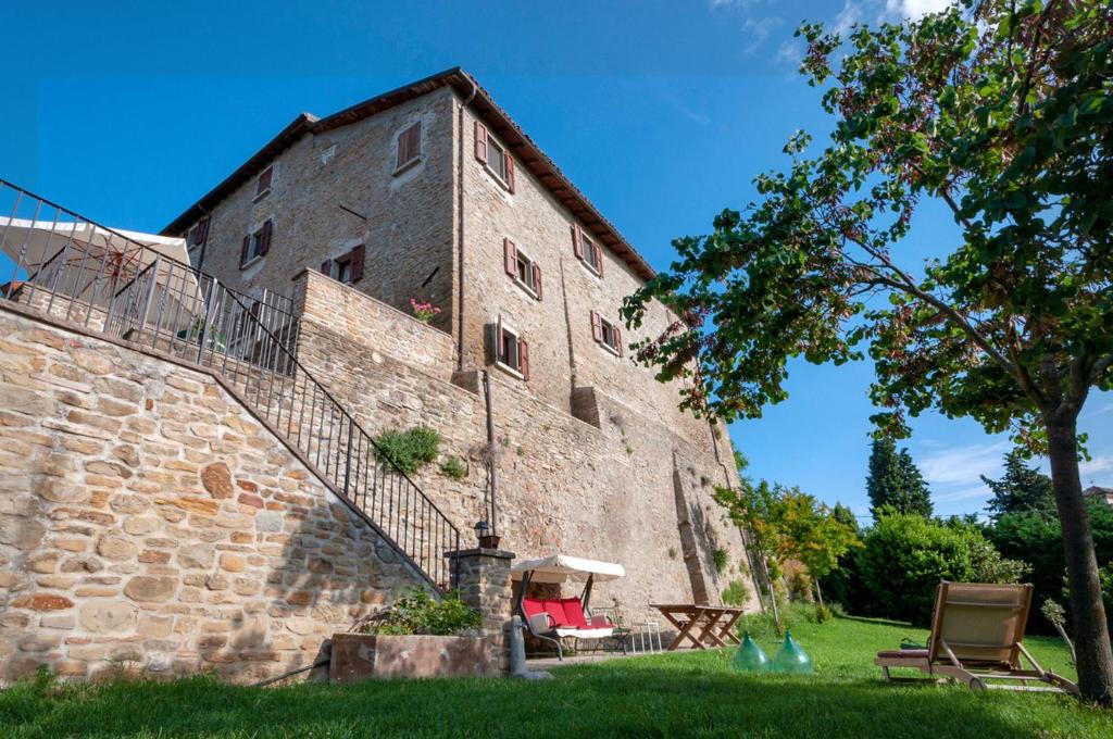 stary kamienny budynek z klatką schodową obok niego w obiekcie Castello Montesasso w mieście Mercato Saraceno