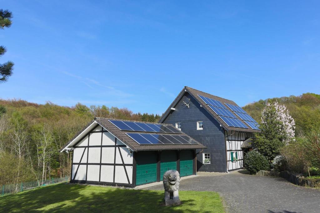 un fienile nero e verde con pannelli solari sopra. di Jagdhaus-Stift-Ennenbach a Ruppichteroth