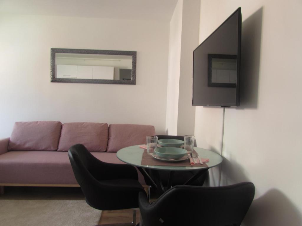 Studio apartman Jordanovac Rebro في زغرب: غرفة معيشة مع أريكة وطاولة مع كراسي