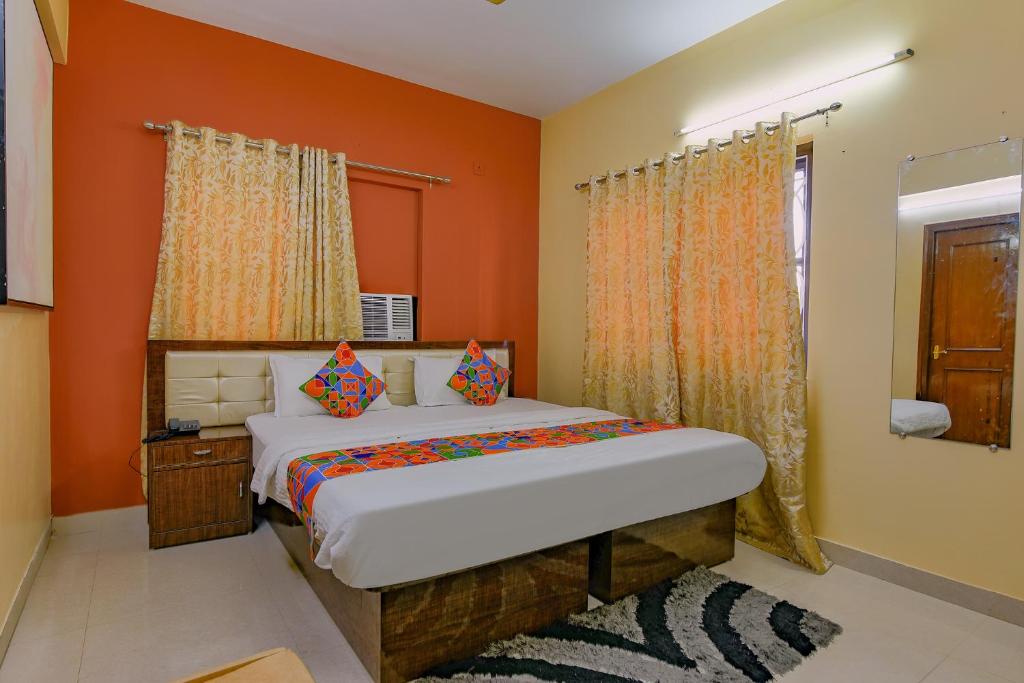 a bedroom with a bed with orange walls and a window at FabHotel New kolkata Residency Inn in Kolkata