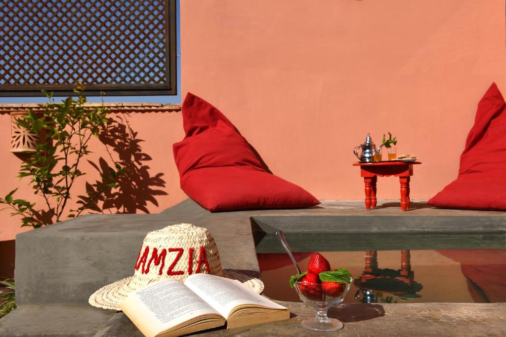 Zimmer mit roten Kissen und einem Buch auf dem Tisch in der Unterkunft Riad Lamzia in Marrakesch
