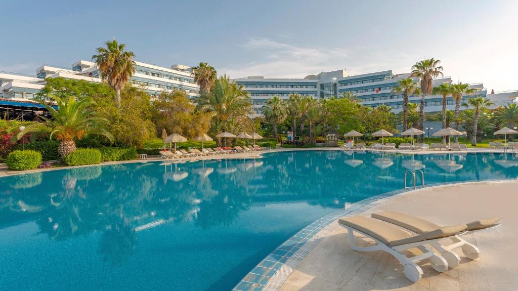 una piscina con sillas y un edificio en Sunrise Resort Hotel, en Kizilagac