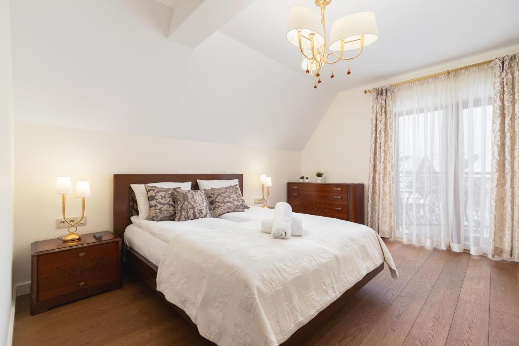 een slaapkamer met een groot bed met witte lakens en een kroonluchter bij Apartament Lux Rezydencja Tatry by Renters Prestige in Zakopane