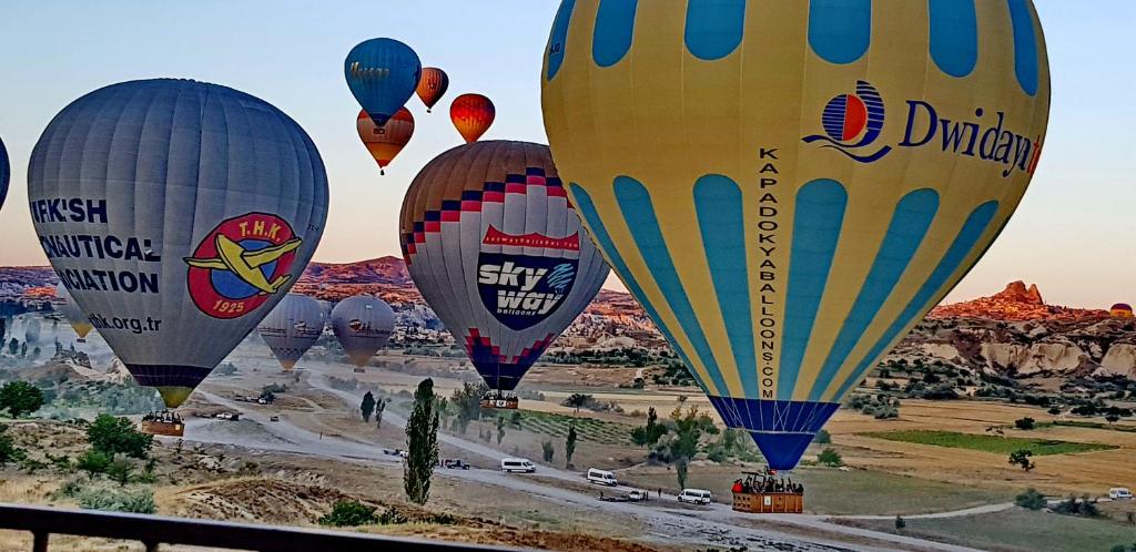 a group of hot air balloons flying over a desert at Muskara Cave Hotel in Göreme