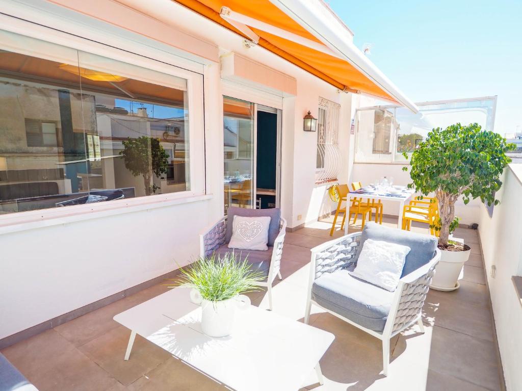 a patio with chairs and a table and a window at Elite Bonaire Penthouse by Hello Homes Sitges in Sitges