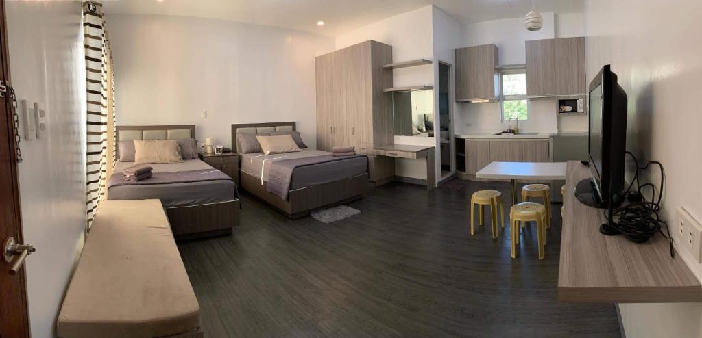 a bedroom with two beds and a desk and a kitchen at Cozy Unit at the heart of Balanga City in Balanga