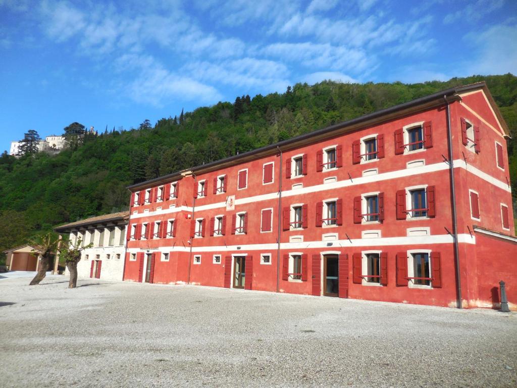 un gran edificio de ladrillo rojo con una montaña en el fondo en Borgo Case Marian, en Cison di Valmarino