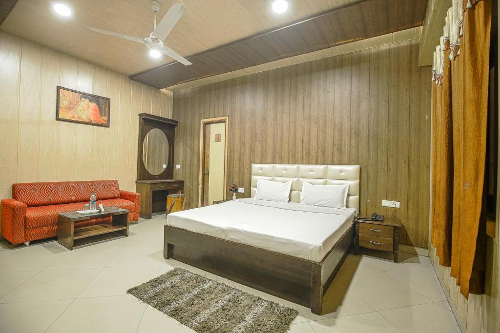 a bedroom with a bed and a red couch at Hotel HK Continental in Amritsar
