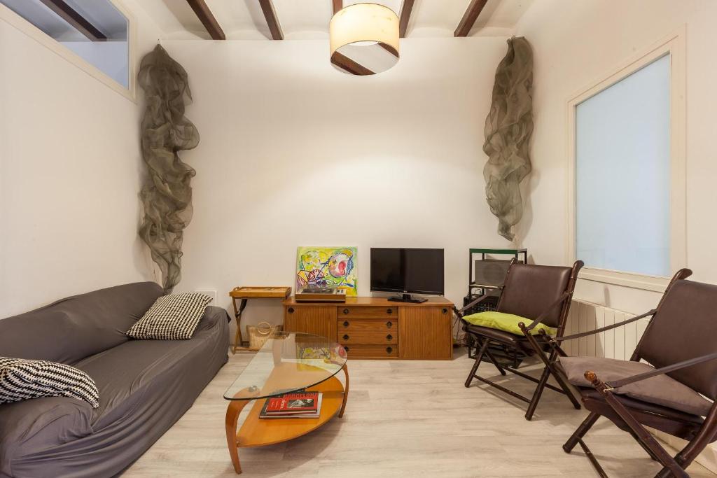 ein Wohnzimmer mit einem Sofa, Stühlen und einem TV in der Unterkunft Monlau 12 in Barcelona