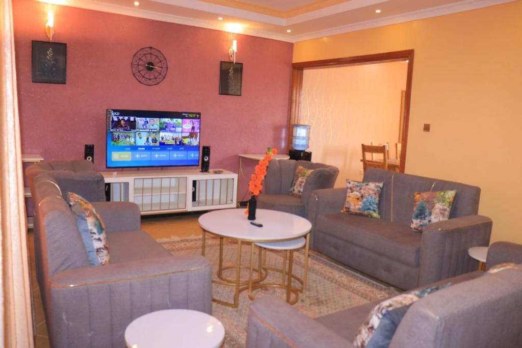 a living room with couches and a flat screen tv at The Glamour House in Juja