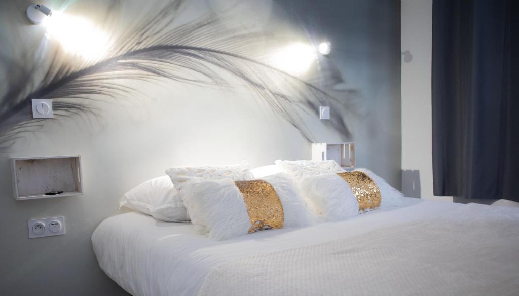 a bed with white sheets and pillows on it at * Les Suites aux Étoiles * in Clermont-Ferrand