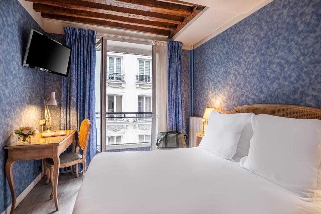 Cette chambre comprend un lit, un bureau et une fenêtre. dans l'établissement Hôtel Baudelaire Opéra, à Paris