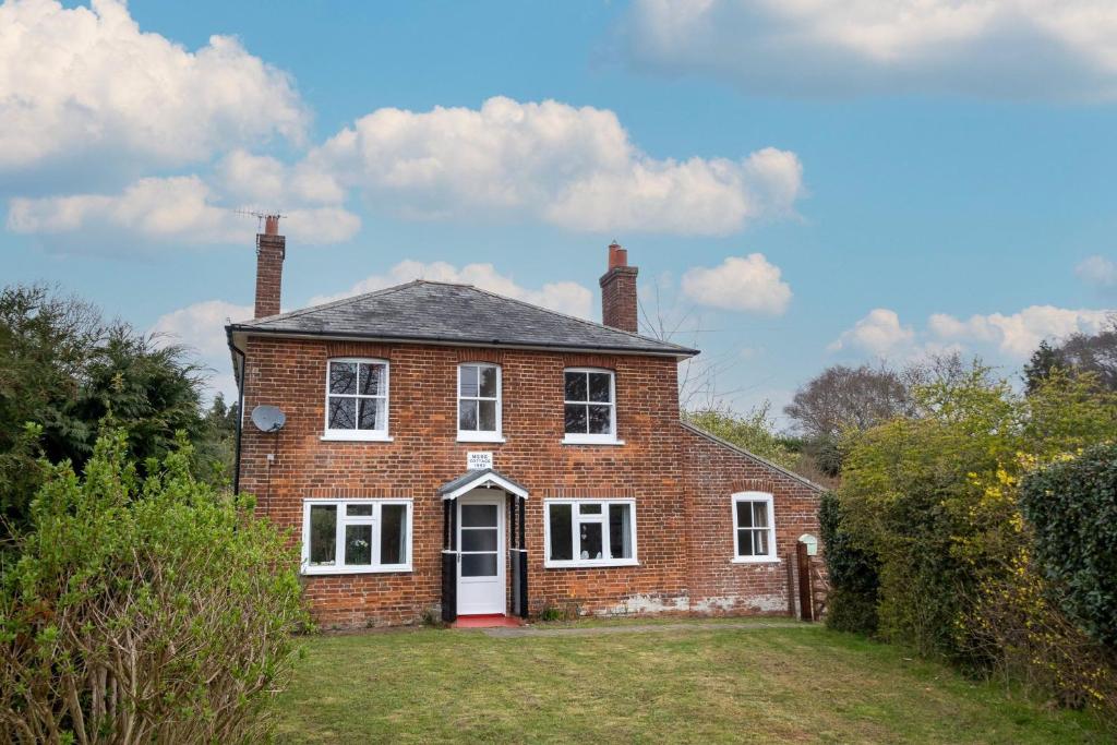 a brick house with a white door on a yard at Mere Cottage - Aldeburgh Coastal Cottages in Thorpeness