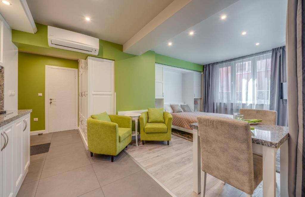 Cette chambre aux murs verts comprend un lit, une table et des chaises. dans l'établissement R & R Apartments, à Sofia