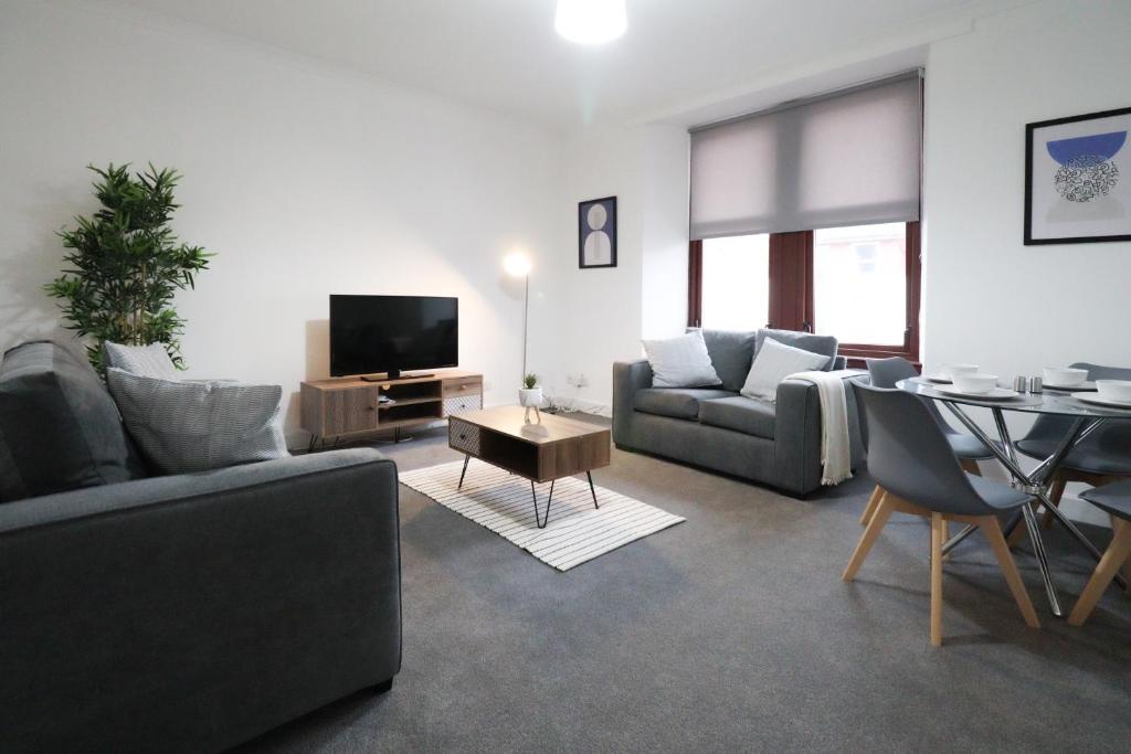 a living room with couches and a table and a television at Sonas Apartment Greenock in Greenock