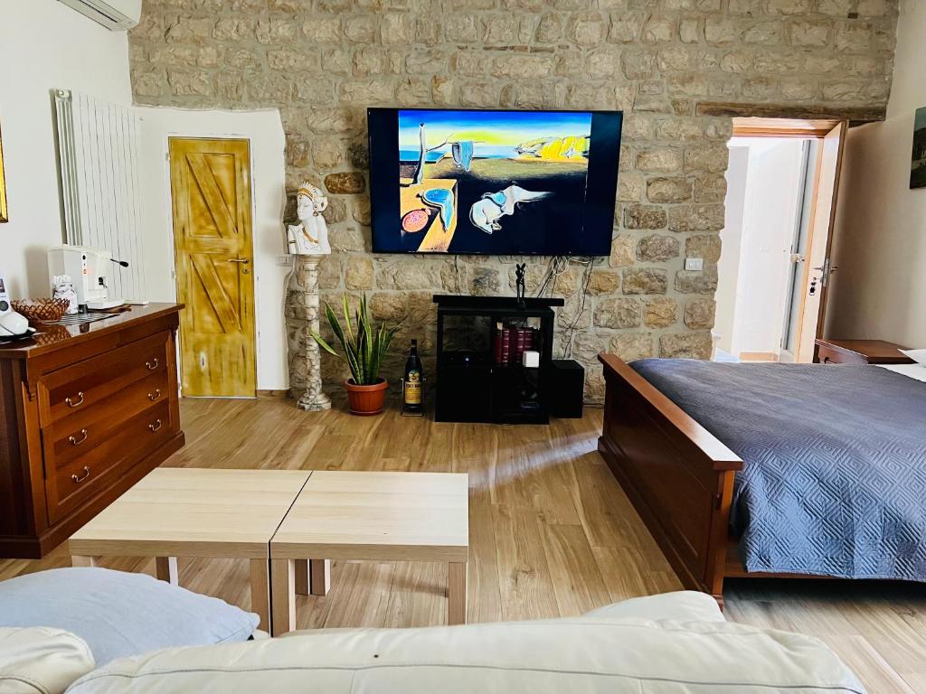 ein Schlafzimmer mit einem Bett und einem TV an einer Steinmauer in der Unterkunft Bombrelais in Apice