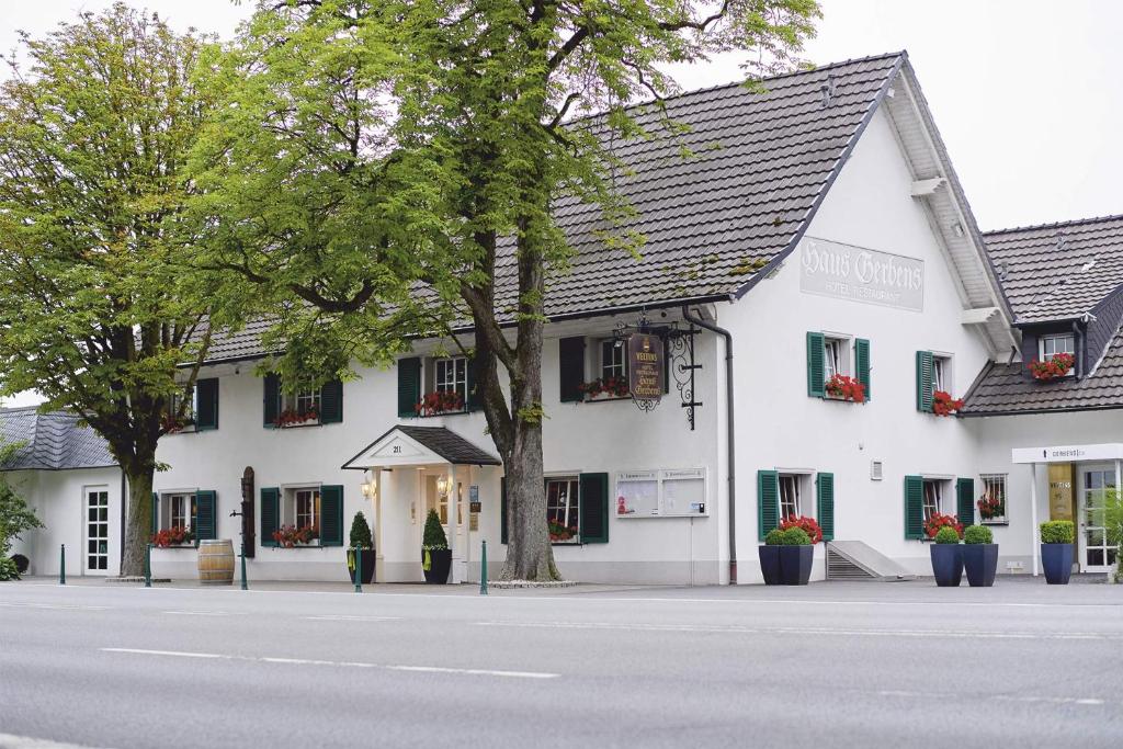 a white building with a tree in front of a street at Haus Gerbens in Wickede (Ruhr)