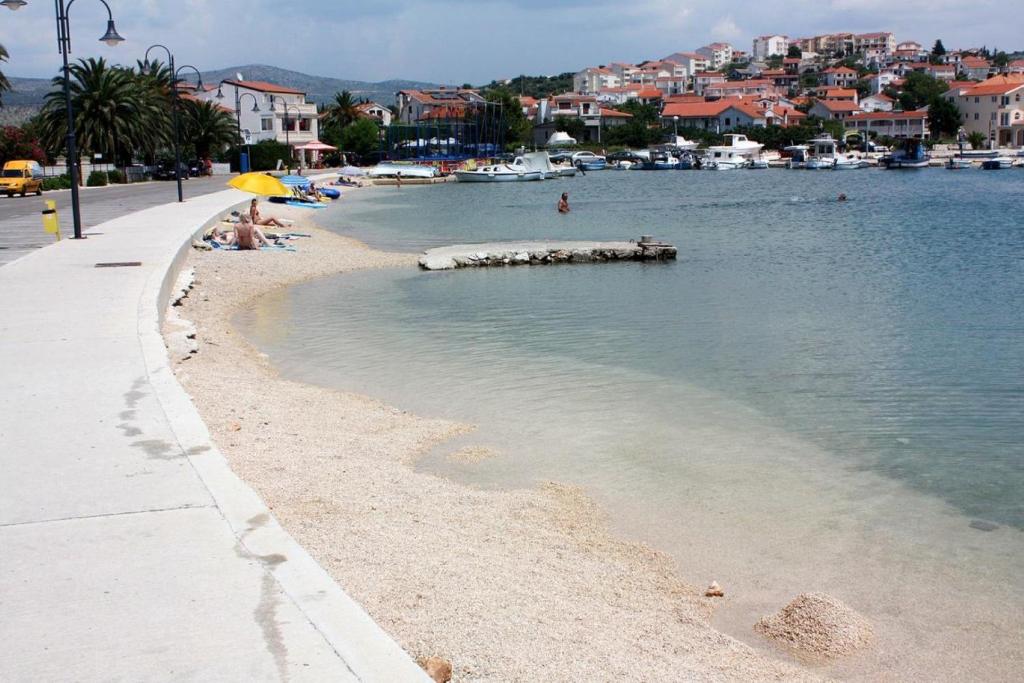 a beach with people sitting under an umbrella at Apartments Lias - with restaurant in Rogoznica