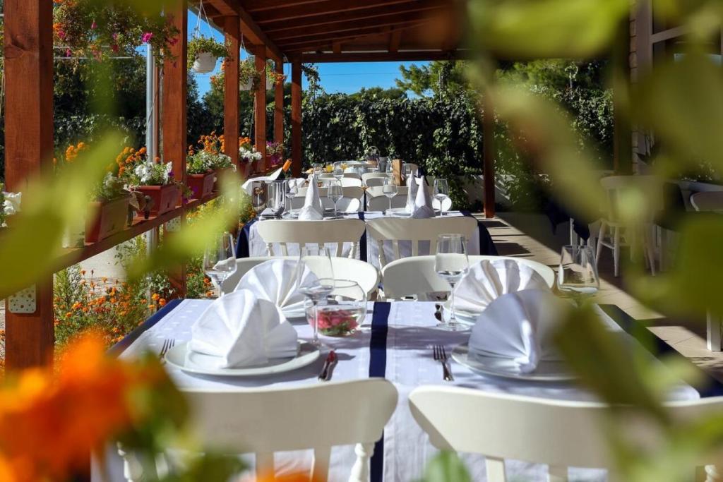 a table set up for a meal with white tables and chairs at Apartments Lias - with restaurant in Rogoznica