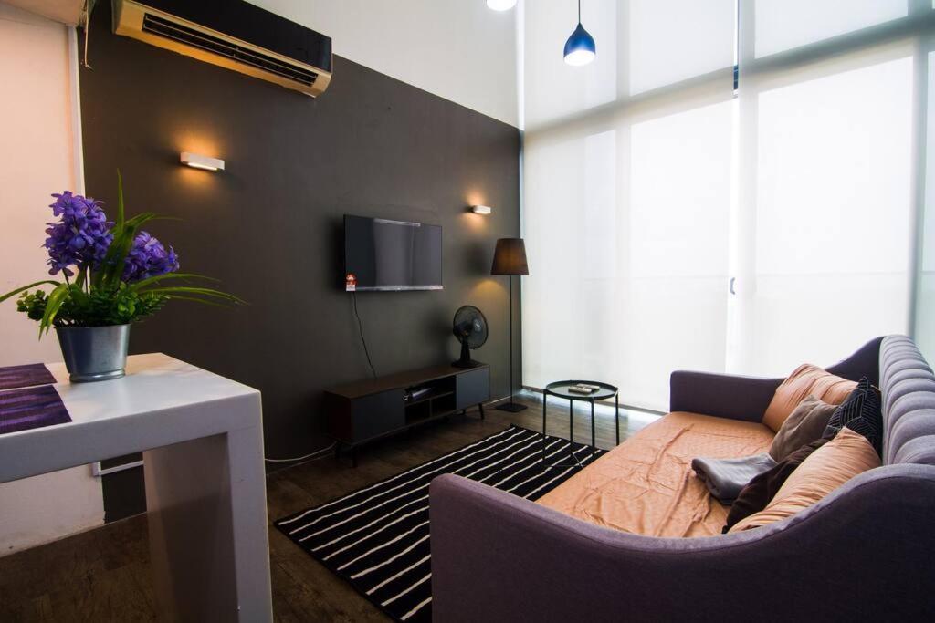 ein Wohnzimmer mit einem Sofa und einem TV in der Unterkunft The Place Cyberjaya by Idealhub in Cyberjaya