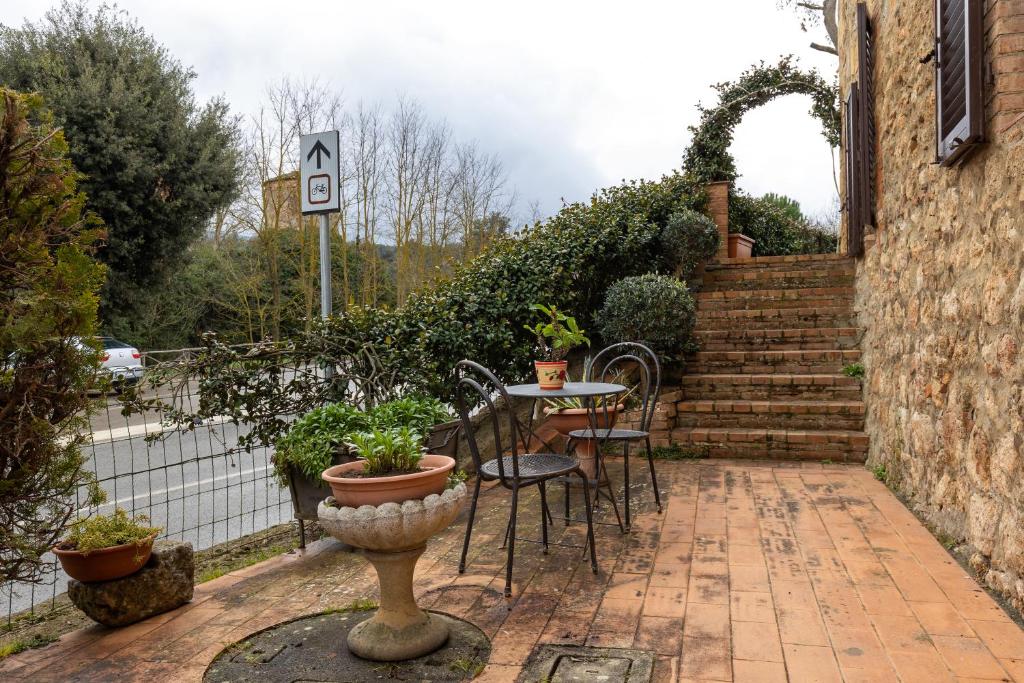 un patio con tavolo, sedie e un edificio di Enchanting Flat with Patio in Abbadia a Isola a Monteriggioni