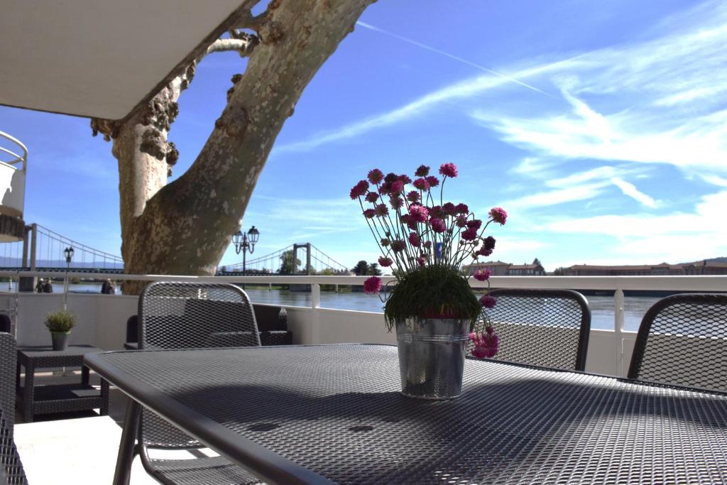 een vaas met bloemen bovenop een tafel bij La Bâtie - Terrasse avec Vue imprenable sur le Rhône, 3 chambres, 3 salles de bain in Tain-lʼHermitage