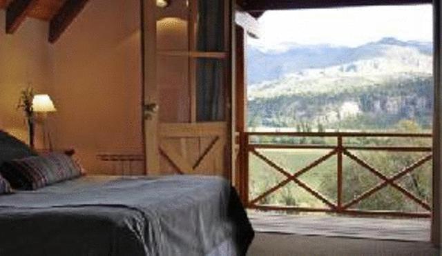 a bedroom with a bed and a large window at Sieteflores Hosteria De Montaña in San Martín de los Andes