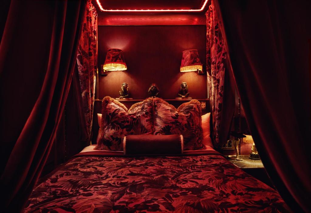 a bedroom with a bed with a red canopy at House of Gods Royal Mile in Edinburgh