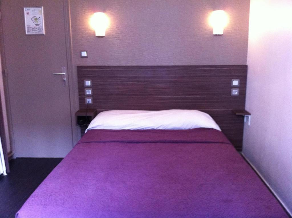 a bedroom with a large bed with a purple blanket at Grand Hôtel Magenta in Paris