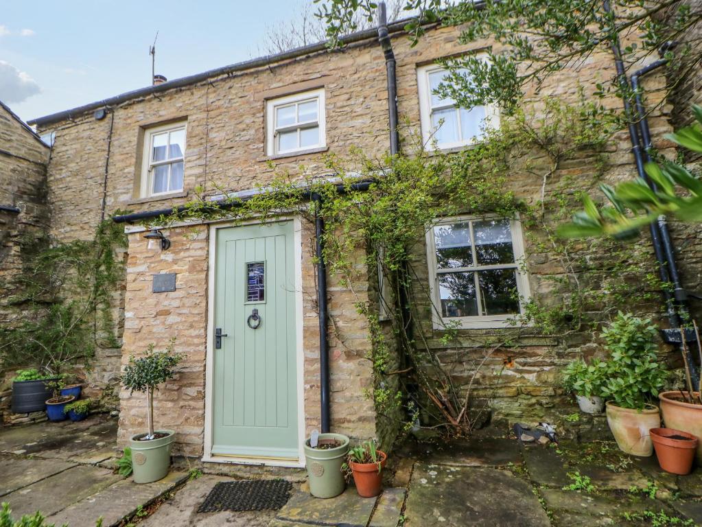 an old brick house with a green door at High House in Hawes