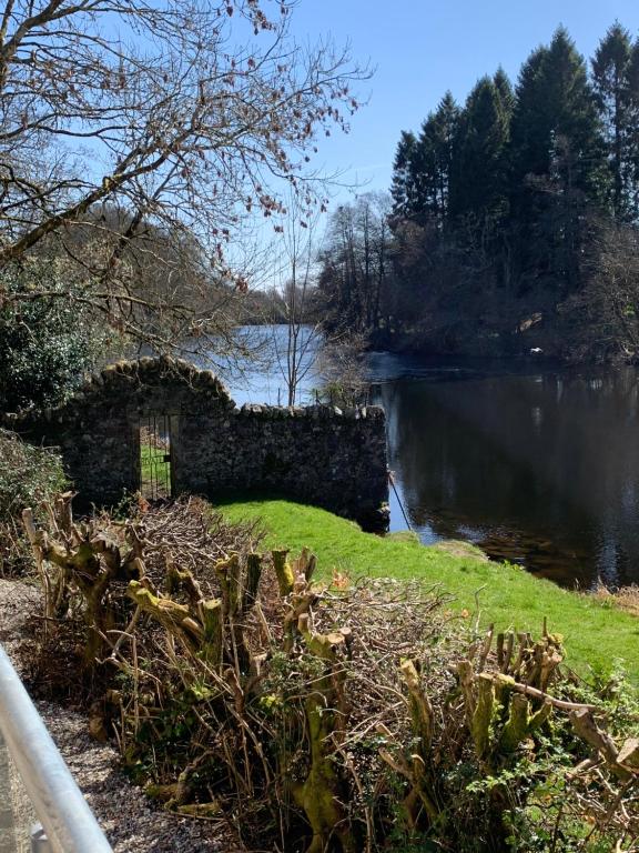 una pared de piedra junto a un cuerpo de agua en Tanllan Apartment, en Callander